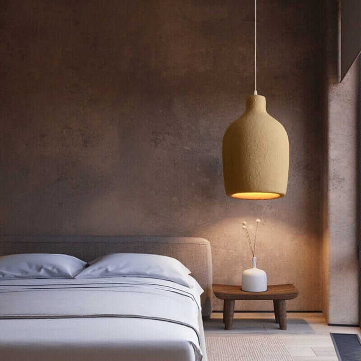 Wabi Sabi Pendant Light hanging above a cozy bed in a minimalist bedroom, providing warm ambient lighting.