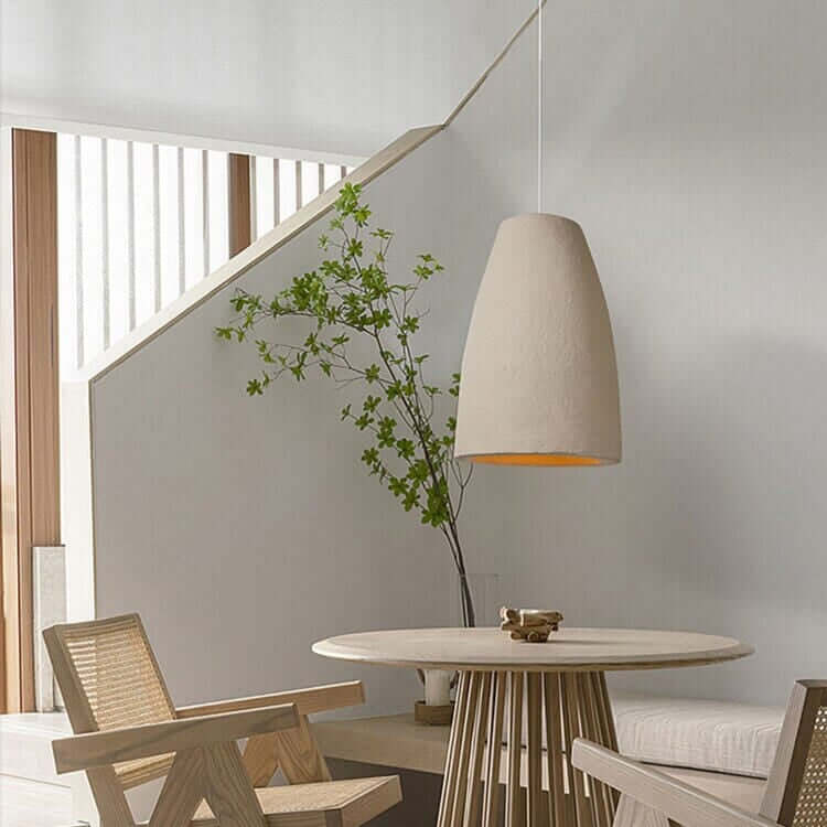 Stylish dining area featuring a Wabi Sabi pendant light, modern chairs, and a circular table with natural decor.