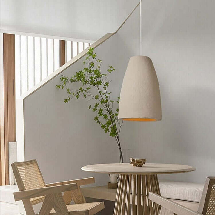 Stylish dining area featuring a Wabi Sabi pendant light, modern chairs, and a circular table with natural decor.