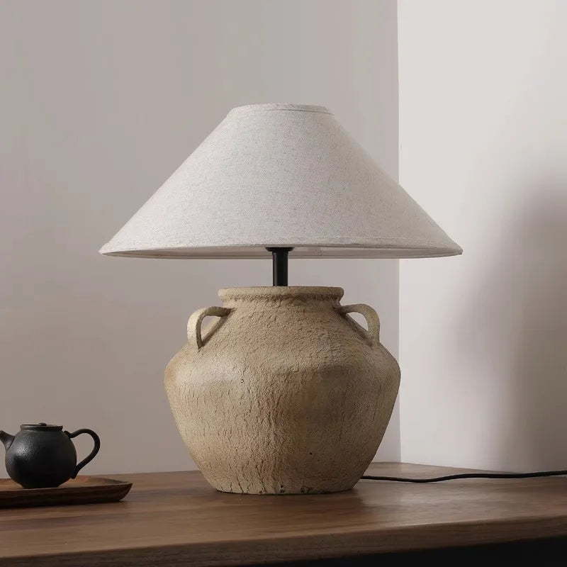 Mid Century Table Lamp - Imperfect Beauty with natural pottery base and minimalist design, emitting warm ambient light.