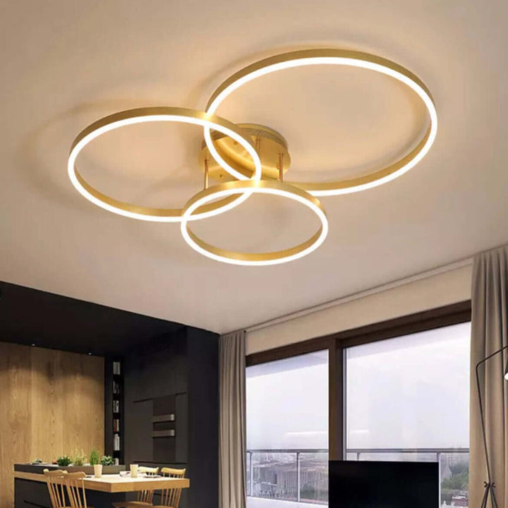 Modern LED chandelier with circular rings illuminating a contemporary living room interior.