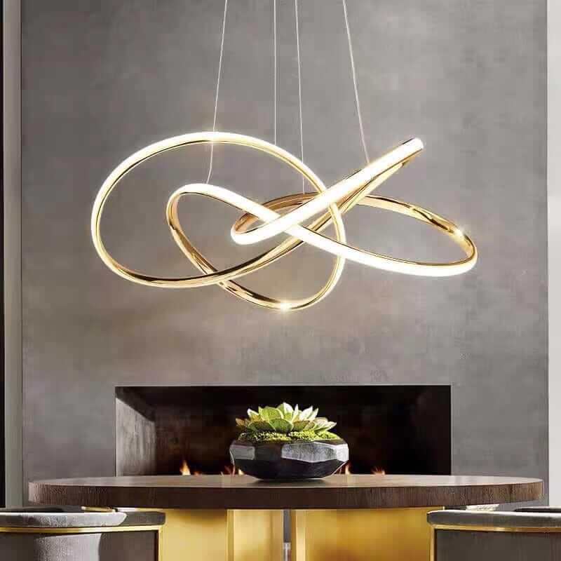 Modern gold chandelier with sleek curves, illuminating a stylish dining area with contemporary elegance.