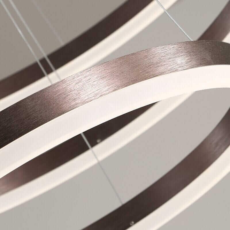Close-up of a modern gold and black chandelier featuring interconnected rings and warm LED glow.