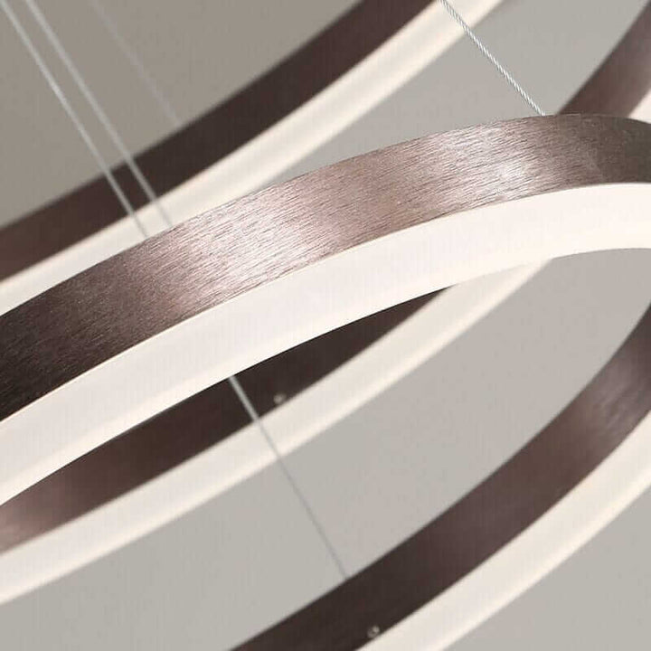 Close-up of a modern gold and black chandelier featuring interconnected rings and warm LED glow.