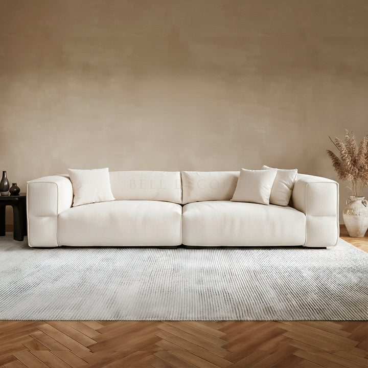 Living Room Sofa Set - Fabric Sofa in creamy ivory with oversized proportions and generous cushioning on a textured rug.