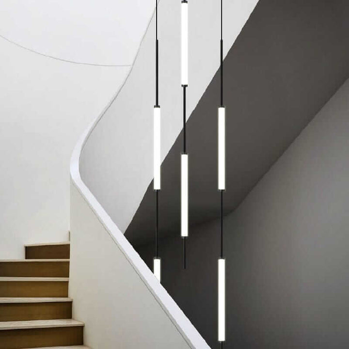 Modern staircase chandelier with sleek pendant lights illuminating a stylish white staircase.